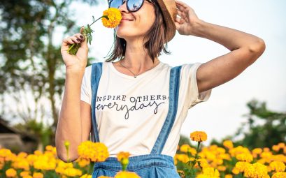 Jeune femme en traun de sentir le parfum d'une fleur jaune dans un champ