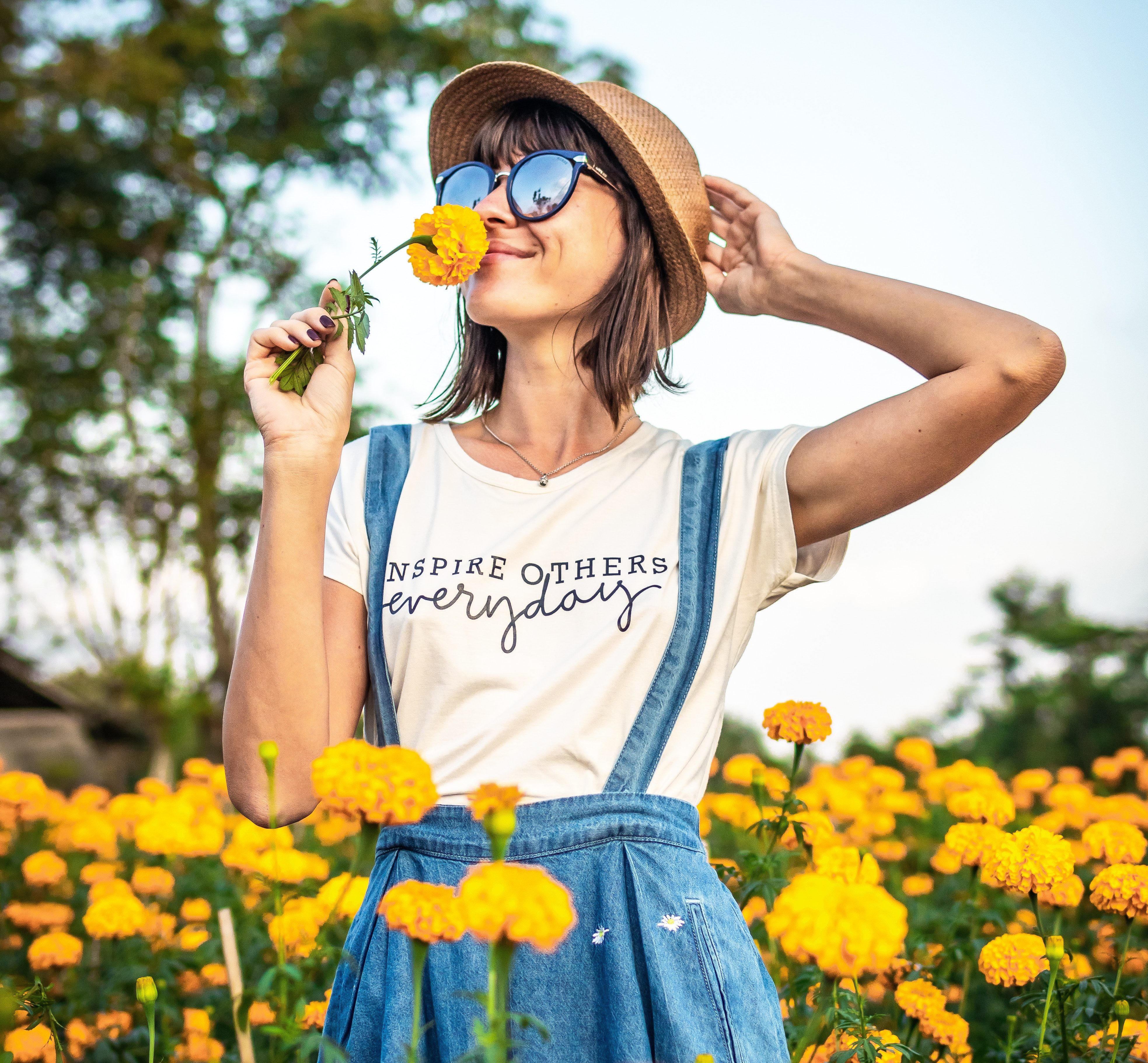 Jeune femme en traun de sentir le parfum d'une fleur jaune dans un champ