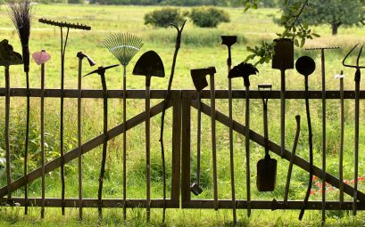 Accessoires pour le jardinage posés debout contre un portail en bois