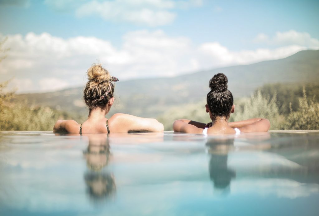 Deux jeunes femmes qui se prélassent dans l'eau chaude de leur piscine